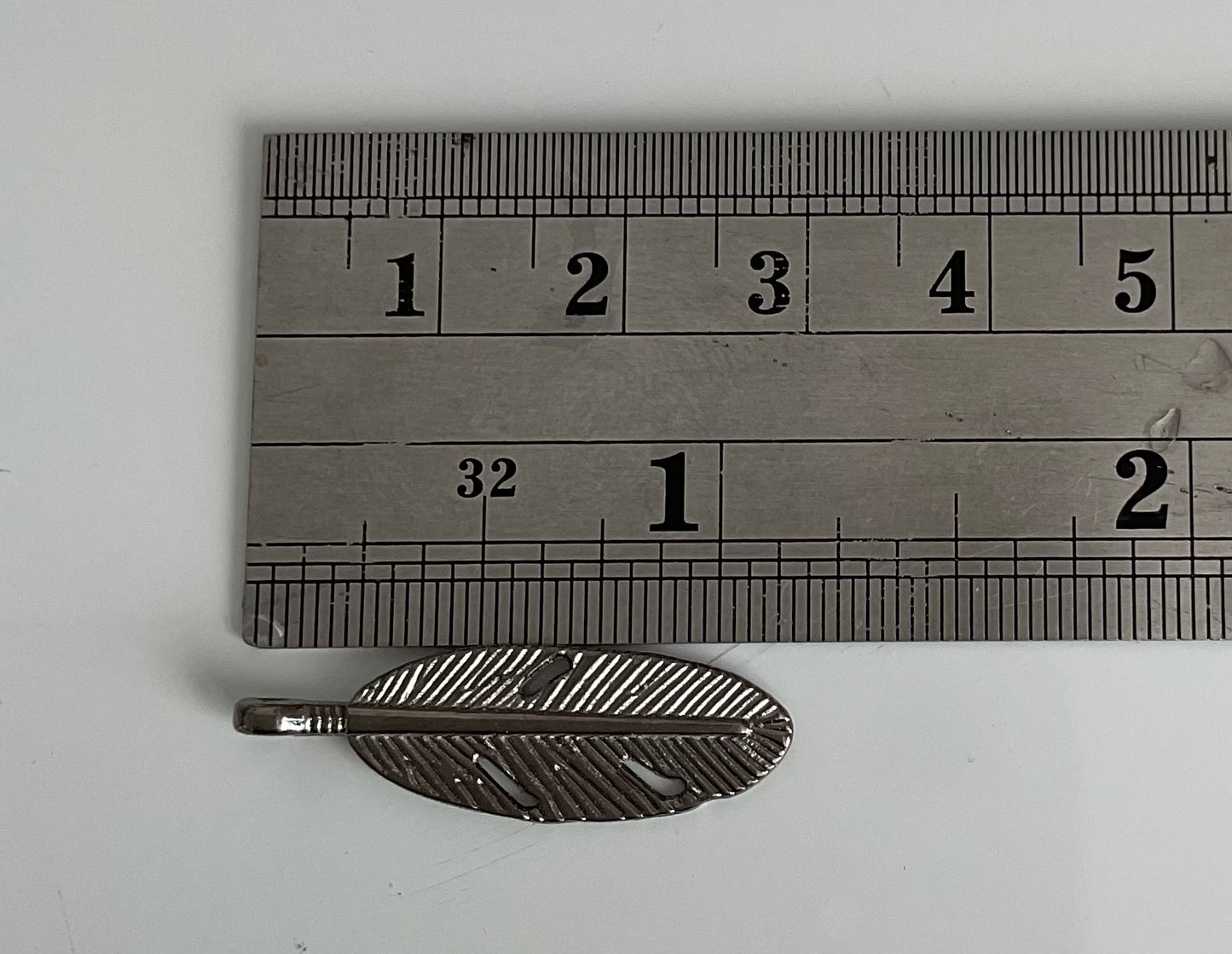 🪶 Nombre: Charm Pluma Metálica